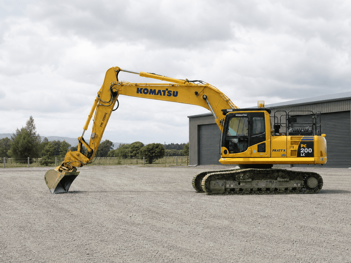 Pratt-liveried Komatsu PC200 LC excavator in a gravel yard.